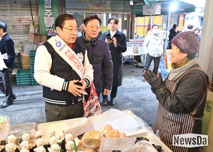 12일 오후 전통시장을 방문한 이현재 하남시장이 직접 장바구니를 들고 점포를 돌며 상인들에게 격려의 인사를 건네고 있다.